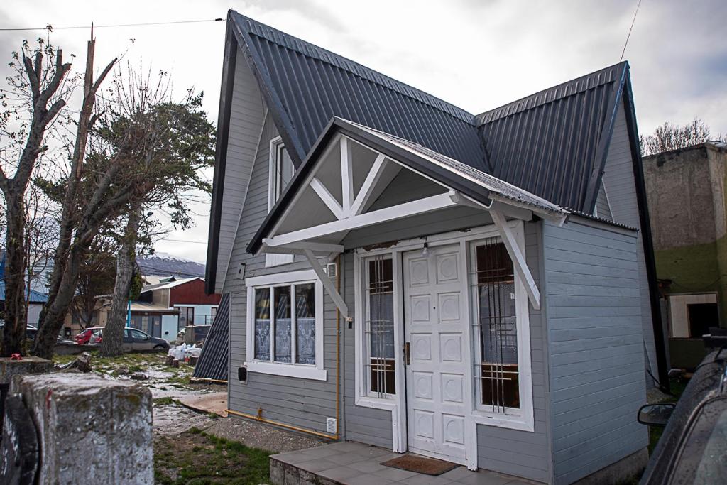 una pequeña casa gris con una puerta blanca en Holger sofus en Ushuaia