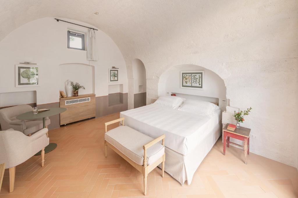 a bedroom with a large white bed and a table at Masseria Auraterrae in Polignano a Mare