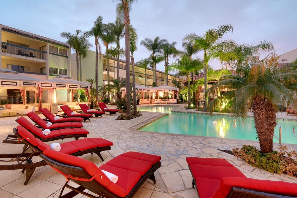 a resort with chairs and a pool with palm trees at Atrium Hotel Orange County in Irvine