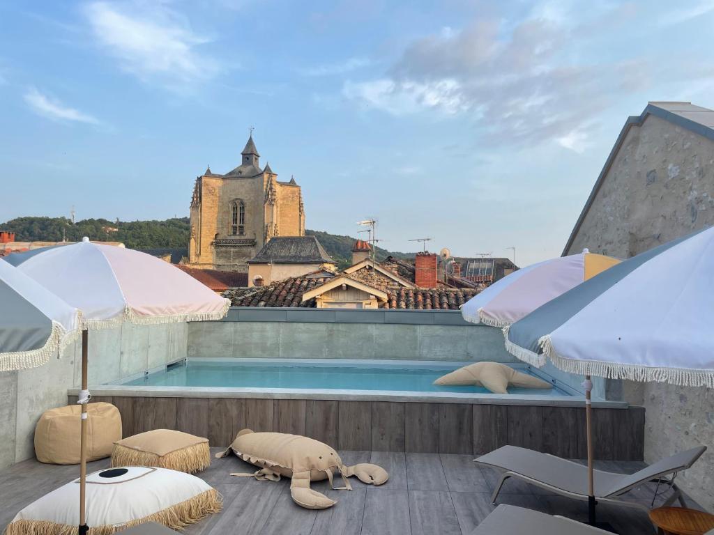 a swimming pool on the roof of a building with umbrellas at Urban Style LES FLEURINES in Villefranche-de-Rouergue