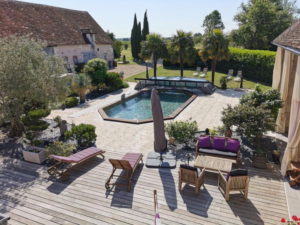 een patio met een zwembad, stoelen en een tafel bij Chambres d'hôtes L'Escale Charmante in Choussy