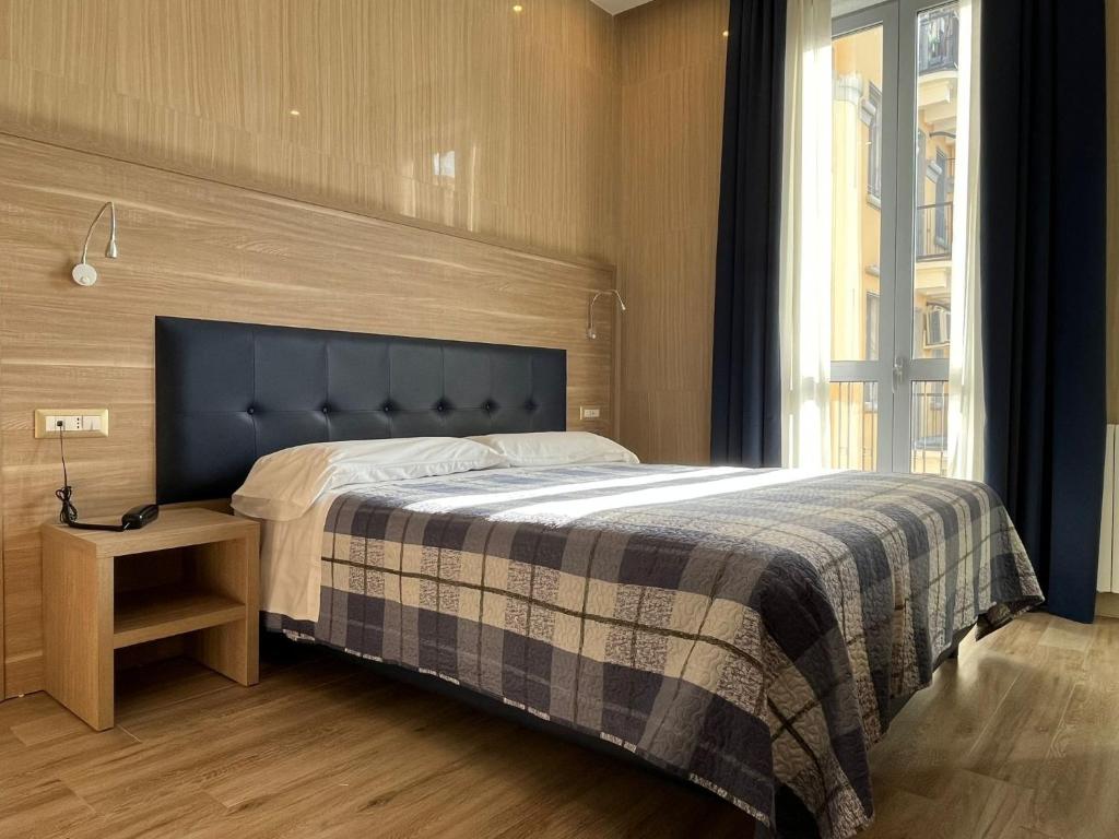 Schlafzimmer mit einem Bett mit blauem Kopfteil und einem Tisch in der Unterkunft Hotel Midway in Mailand