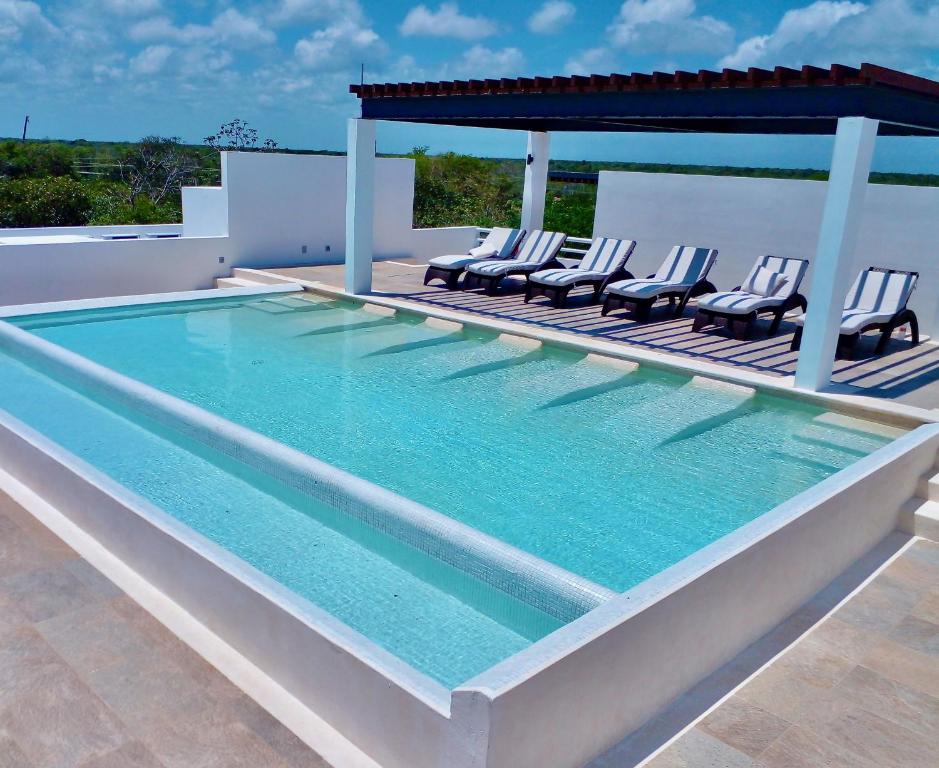 una grande piscina con sedie e gazebo di Condominio en la Riviera Maya ad Akumal