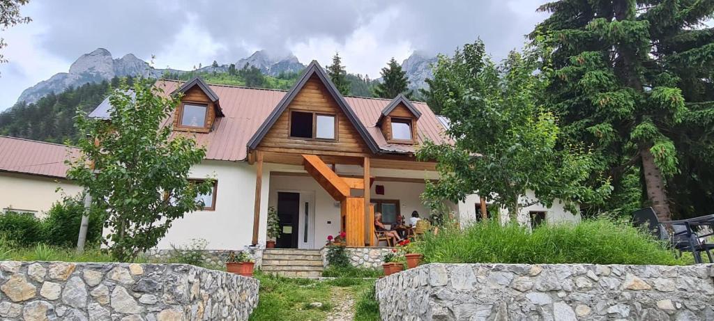 una casa en las montañas con una valla de piedra en Bujtina Albjoni en Valbonë