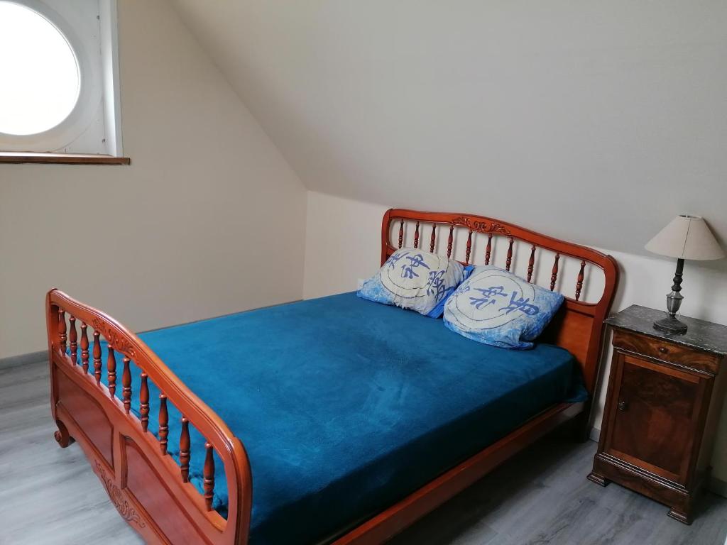 1 dormitorio con 1 cama de madera y 2 almohadas azules en Maison où il fait bon se reposer en Onzain