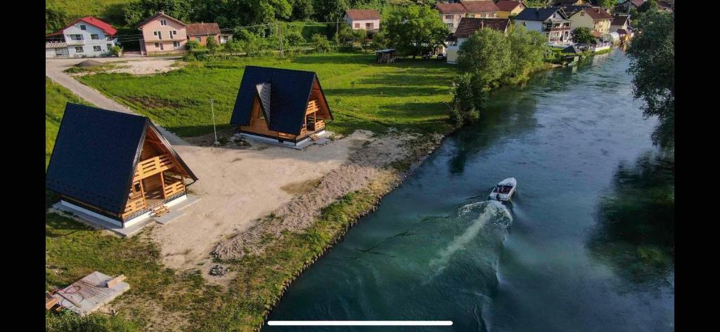 a boat traveling down a river with two huts at Bungalow Jajce 2 Cottage in Jezero