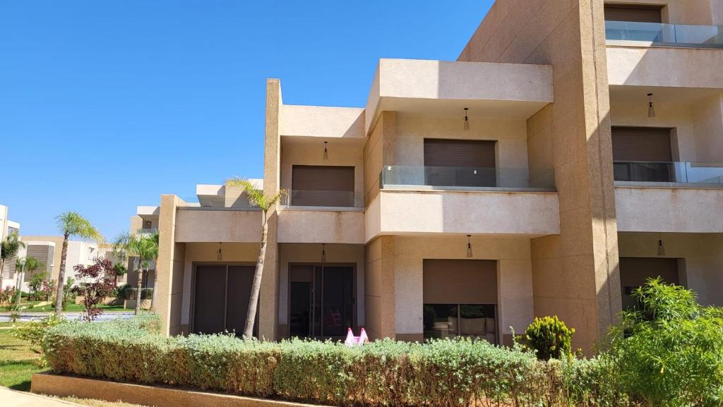 un edificio con una palmera delante de él en Villa de luxe residence tamaris marina 6 piscines jardin parking, en Saidia 
