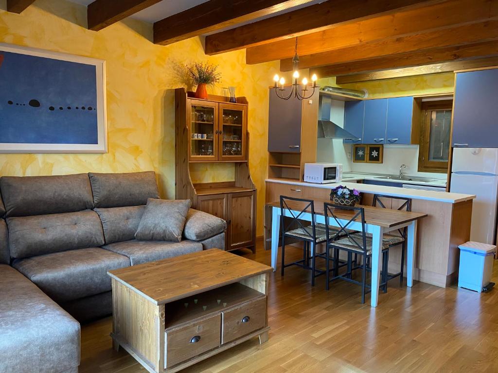 een woonkamer met een bank en een tafel en een keuken bij Duplex Altos de Santiago Jardin in Villanúa