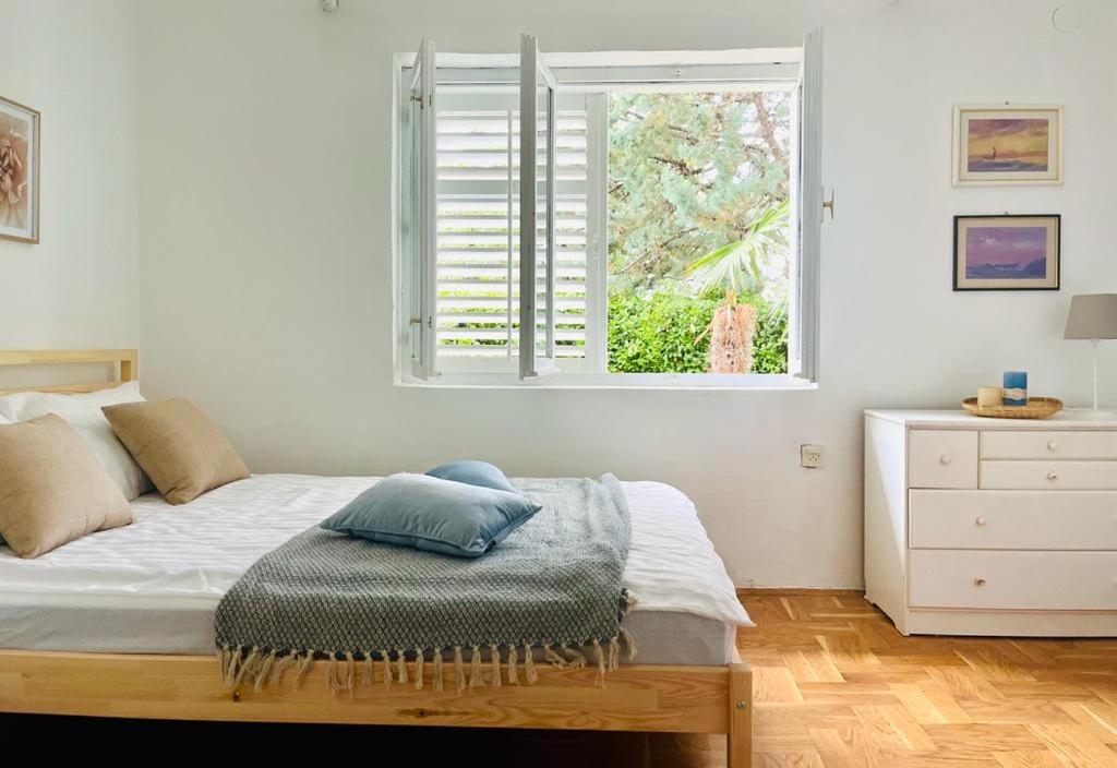 a white bedroom with a bed and a window at Blue Horizon in Novi Vinodolski