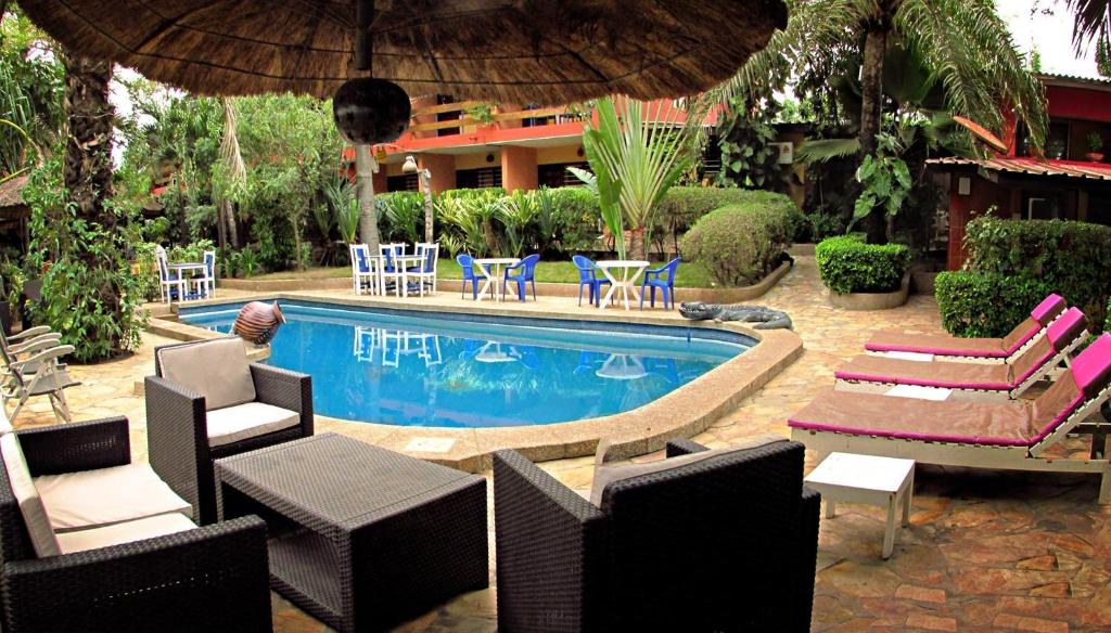 uma piscina com cadeiras, uma mesa e um guarda-sol em Hotel Napoleon Lagune em Lomé