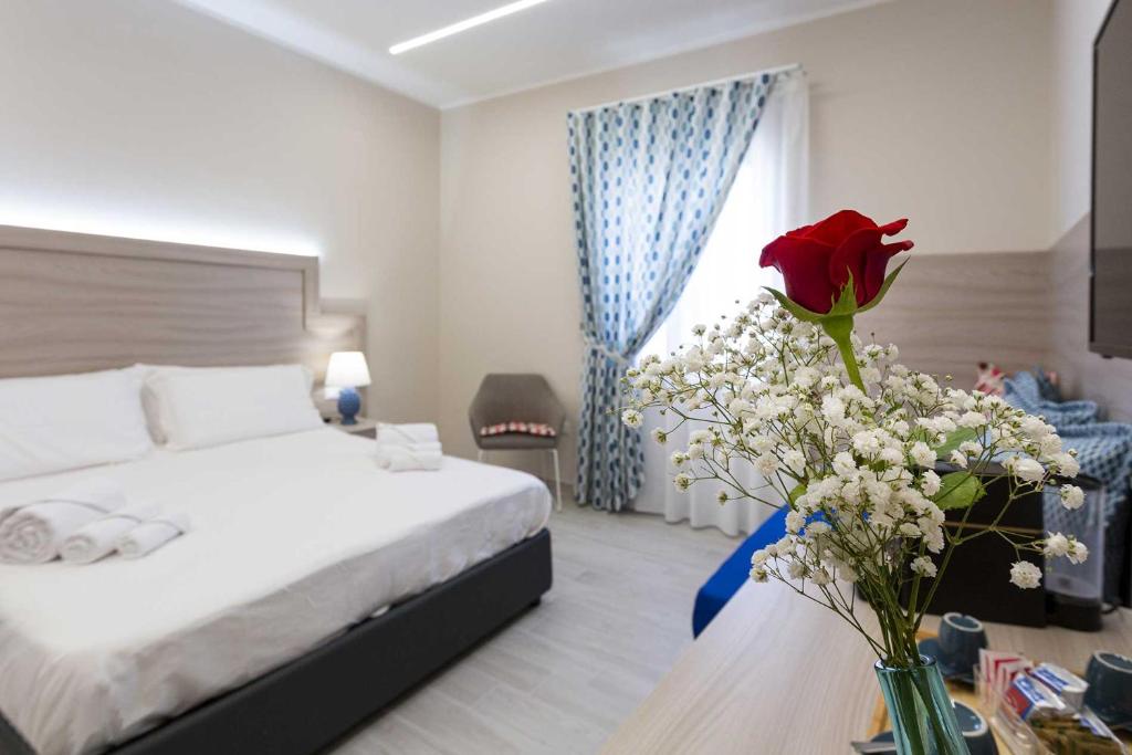 Agorà Vulcano في Crosia: غرفة نوم بسرير و مزهرية مع وردة على طاولة