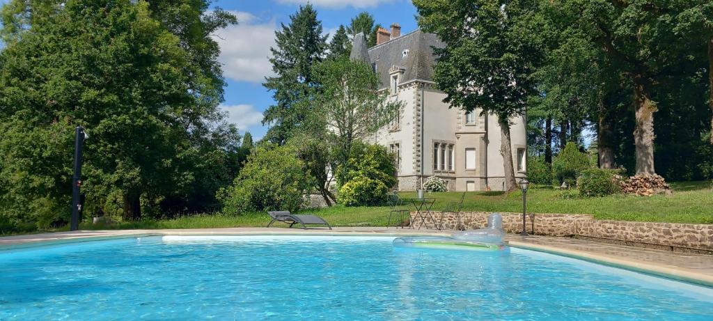 una grande piscina di fronte a una casa di Chateau Maleplane a Saint-Léonard-de-Noblat