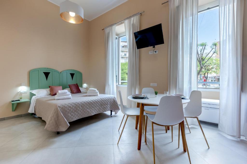 1 dormitorio con 1 cama, mesa y sillas en Bonnystudios Holiday Apartments en Cagliari