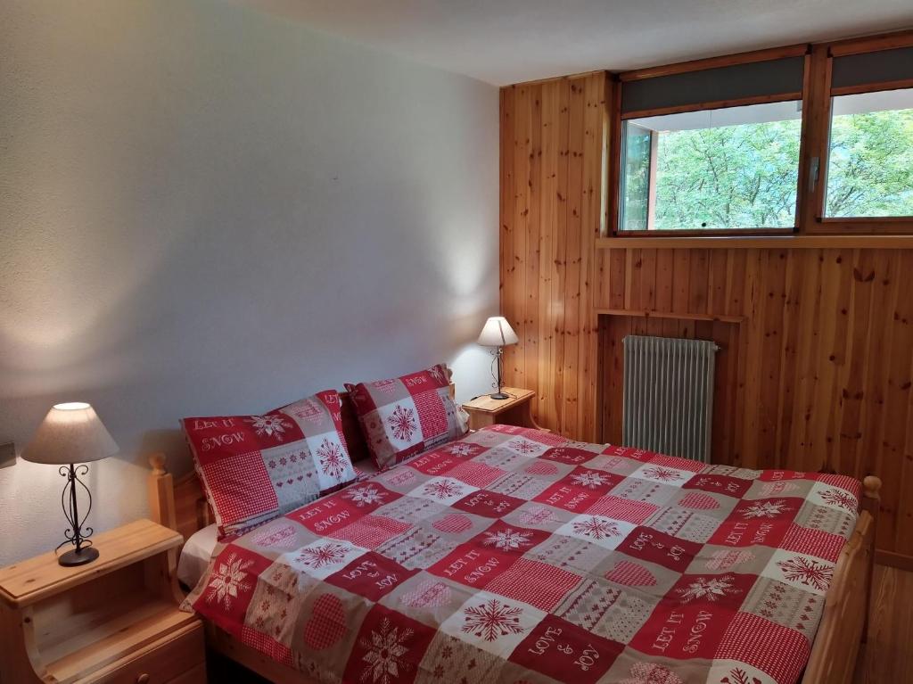 a bedroom with a bed with a red and white quilt at Appartamento I Larici in Folgarida
