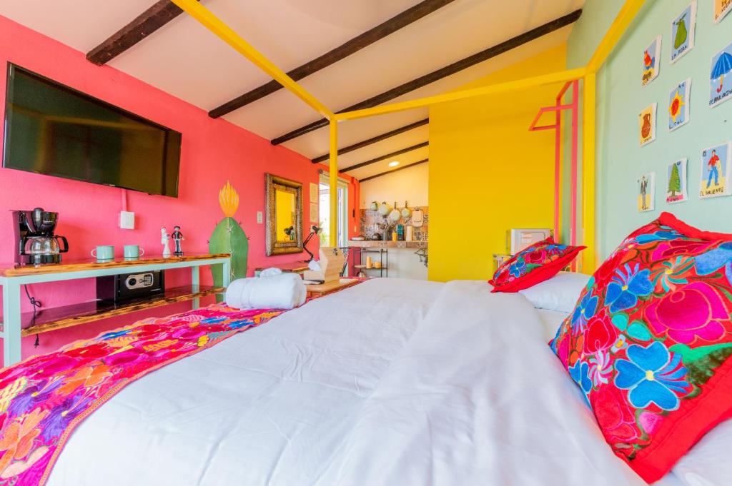 Dormitorio con cama blanca y paredes coloridas en Casa Colibrí Malecón, en Puerto Vallarta