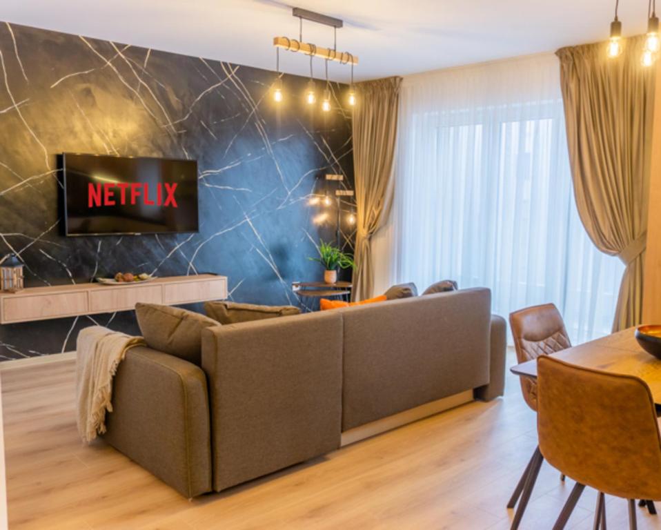 een woonkamer met een bank en een tv aan de muur bij Balance Apartments Complex Qualis Brasov in Braşov