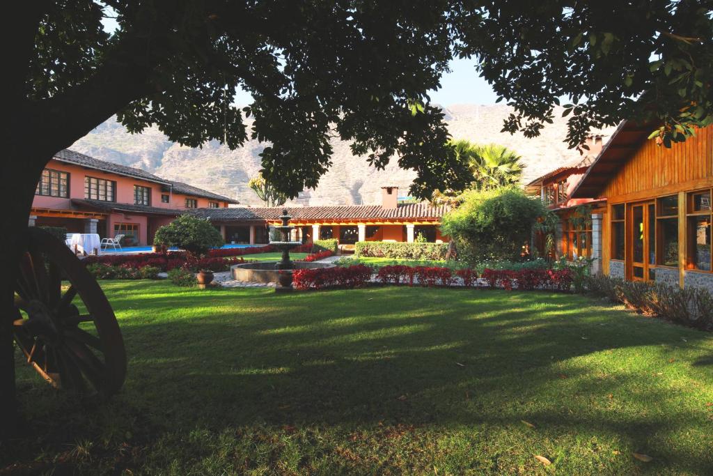 a green yard with a house and a building at Hotel San Agustin Urubamba in Urubamba
