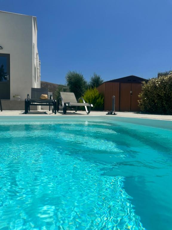 a swimming pool with blue water in a yard at Casa di Somnia Luxury Suites and Villas in Marmari