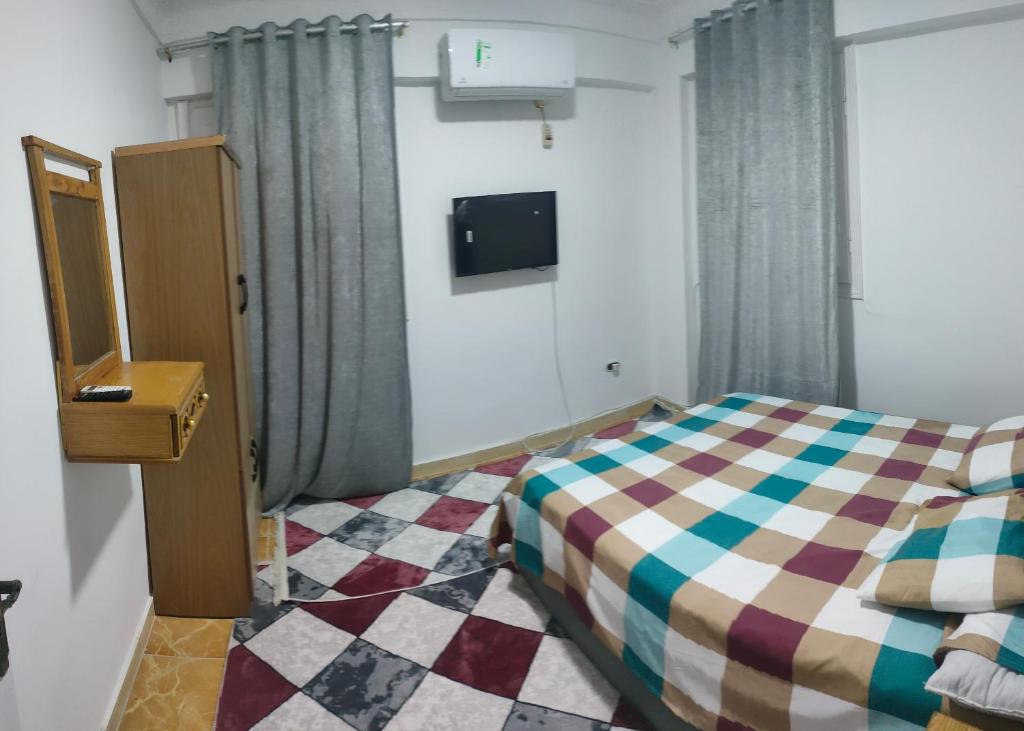 ein kleines Schlafzimmer mit einem Bett und einem TV in der Unterkunft العجمى الكيلو 21 شاطئ النخيل in Alexandria