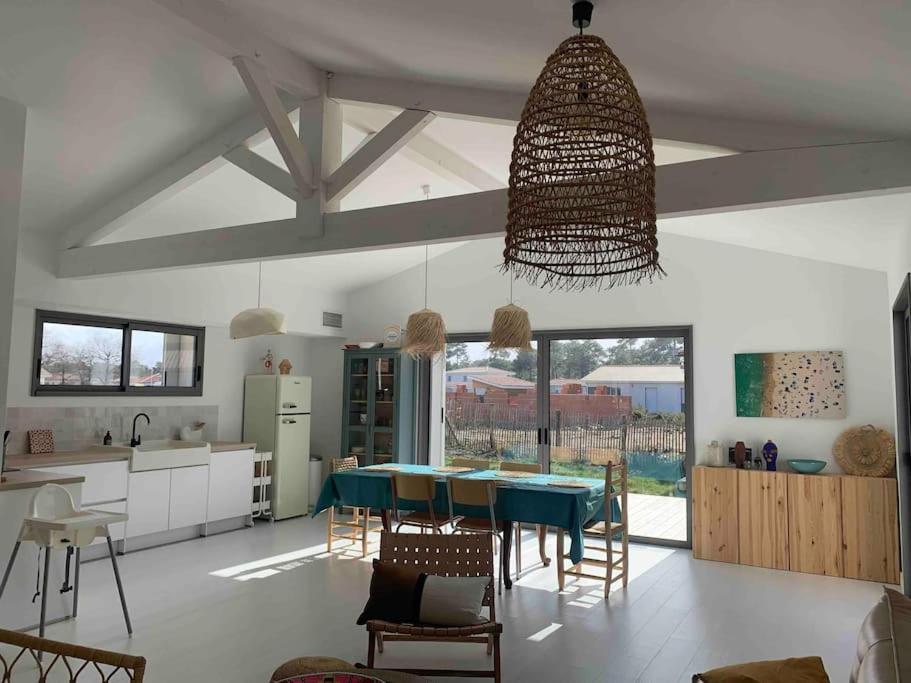 une cuisine et une salle à manger avec une table et des chaises dans l'établissement Maison de plage Montalivet, à Vensac