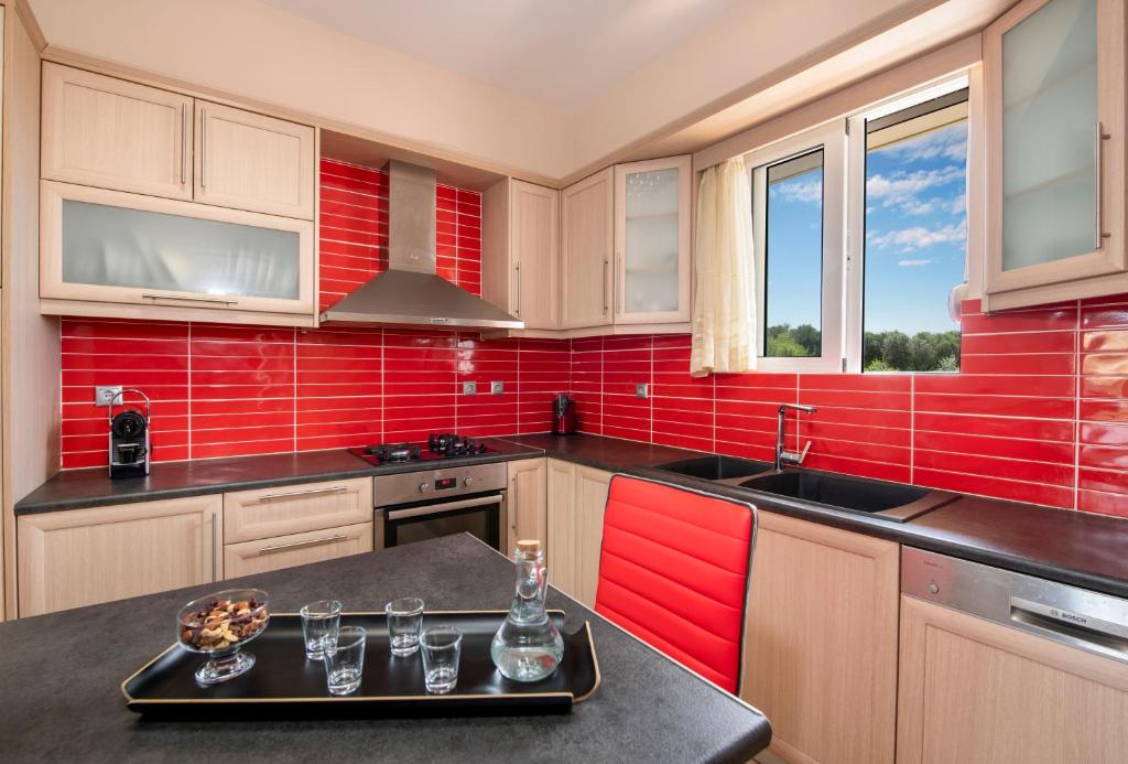 a red kitchen with a black counter and a red wall at Valia's House in Kato Daratso