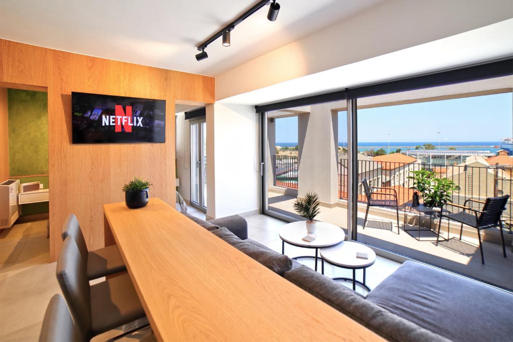 a living room with a couch and a large window at Heraklion Harbour Penthouse in Heraklio Town