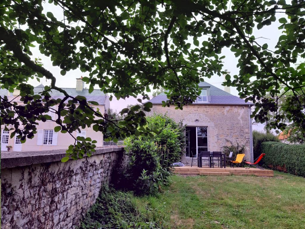 a house with a stone wall and a yard at Le Pavillon du Manoir de Conjon in Crouay