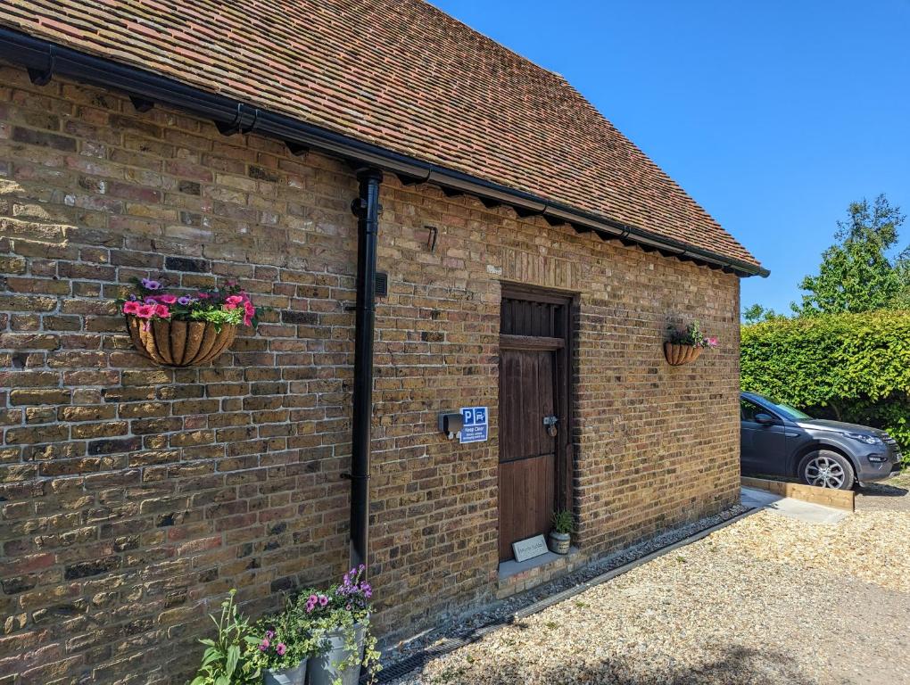 a brick building with a door and flowers on it at Myrtle Stables - converted, self-contained, countryside in Hernhill