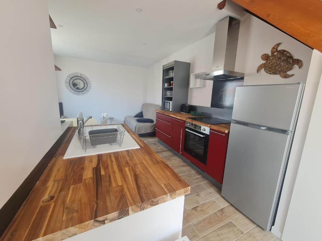 une cuisine avec des armoires rouges et un réfrigérateur blanc dans l'établissement Maison La tranche sur Mer proche centre ville et plages, à La Tranche-sur-Mer