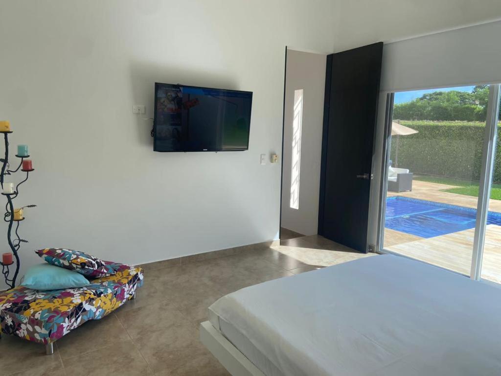 um quarto com uma cama e uma televisão na parede em Girardot Casa estilo mediterraneo con piscina privada em Girardot