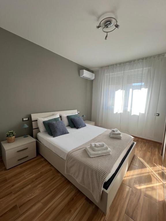 a white bedroom with a large bed with blue pillows at Welcome Home Quartu Sant'Elena in Quartu SantʼElena