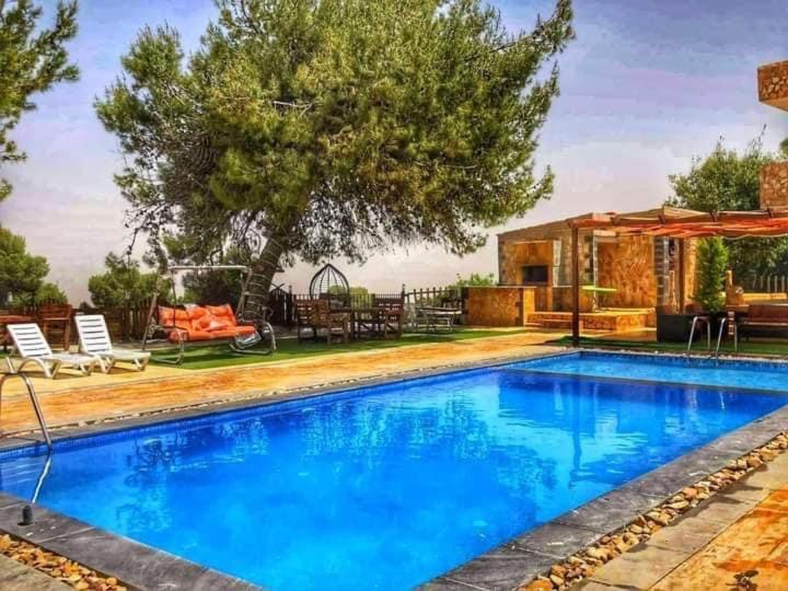 una piscina con acqua blu di fronte a una casa di Talet kokash ad Al-Salṭ