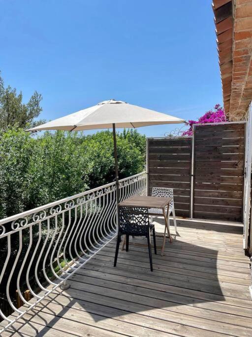une table et une chaise avec un parasol sur une terrasse dans l'établissement Grand Studio & Terrasse Privée, à Hyères