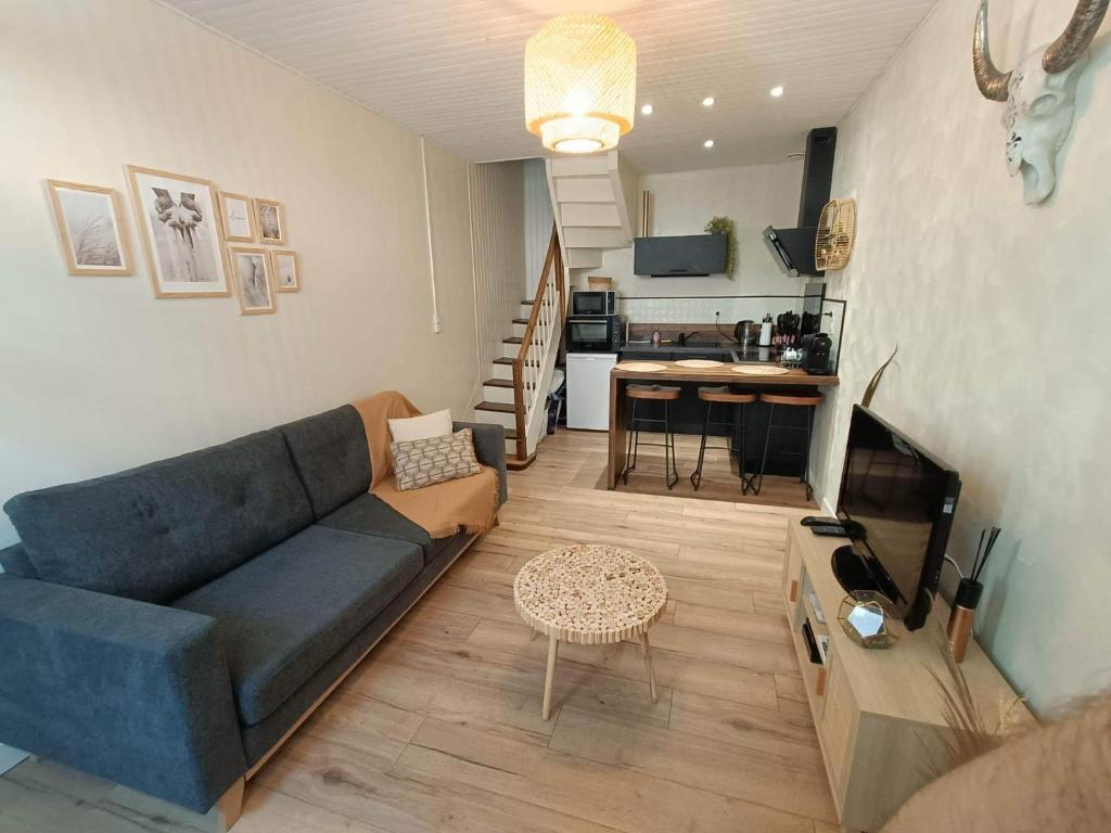 ein Wohnzimmer mit einem blauen Sofa und einer Küche in der Unterkunft Joli cocon en hyper centre in Loudéac