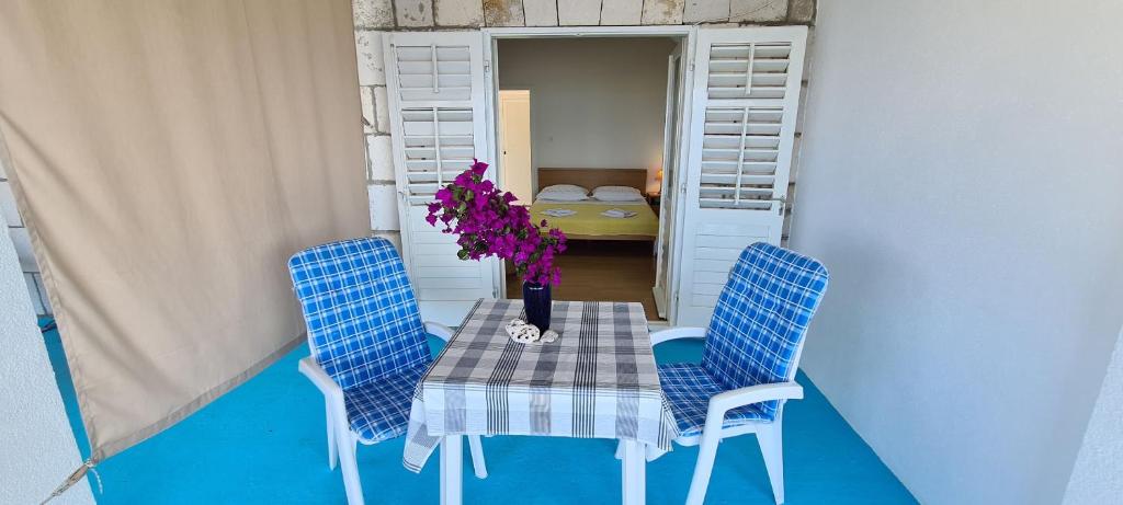 einen Tisch mit zwei Stühlen und eine Vase mit Blumen darauf in der Unterkunft Apartments Lanterna in Sućuraj