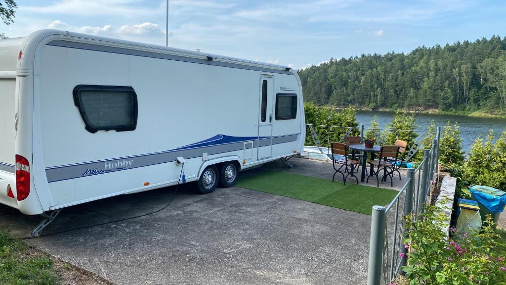 a white trailer parked on a patio next to a table at Luksusowy Kemping in Leśna