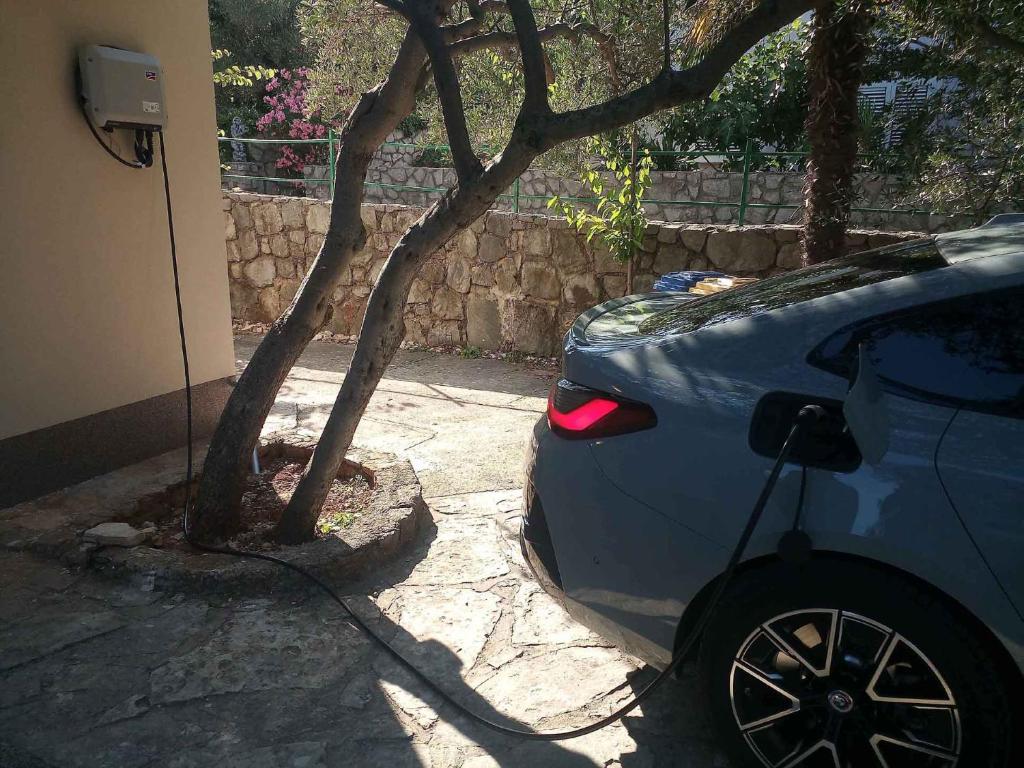 samochód zaparkowany obok drzewa obok domu w obiekcie Garden Apartment Braut w mieście Kornić