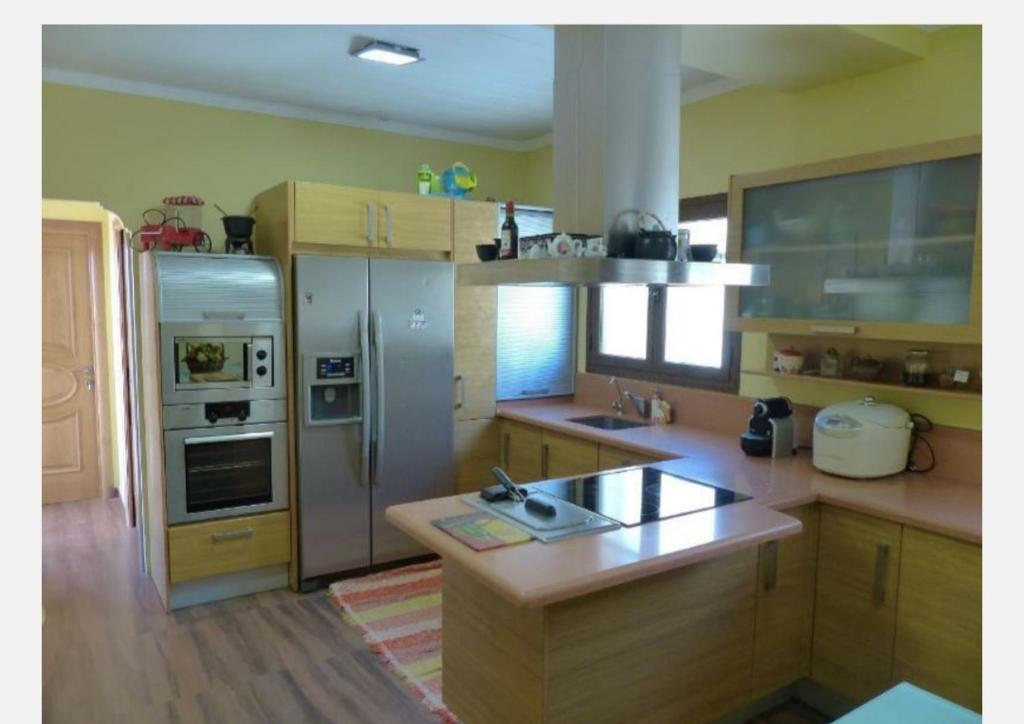 una cocina con armarios de madera y electrodomésticos de acero inoxidable en Villa Reencuentro, en Mojácar