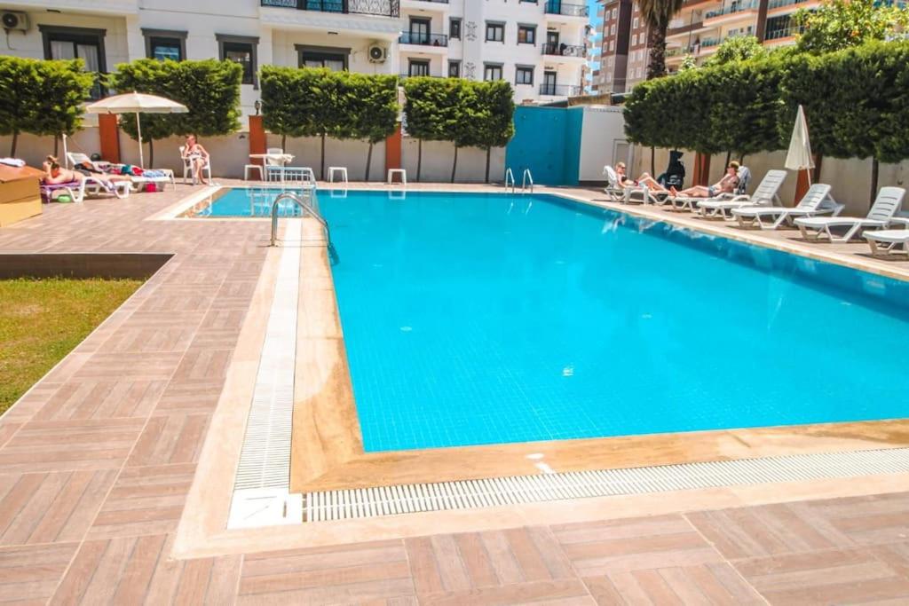 una piscina en un hotel con gente sentada alrededor en ABR 5 Residence en Alanya