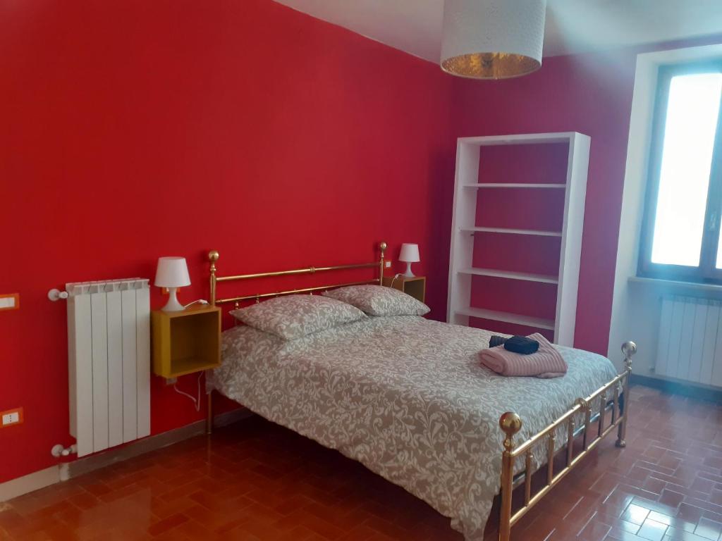 1 dormitorio con cama y pared roja en Tuscany, Pontremoli, Italy Swallows Court Lovely home sleeps 2 to 4 people, en Pontremoli