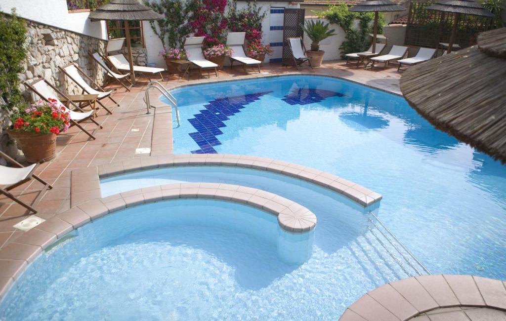 - une grande piscine avec des chaises et des chaises dans un complexe dans l'établissement Hotel Barsalini, à SantʼAndrea