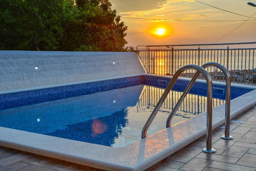 a swimming pool with a sunset in the background at Apartman GROMILA in Senj