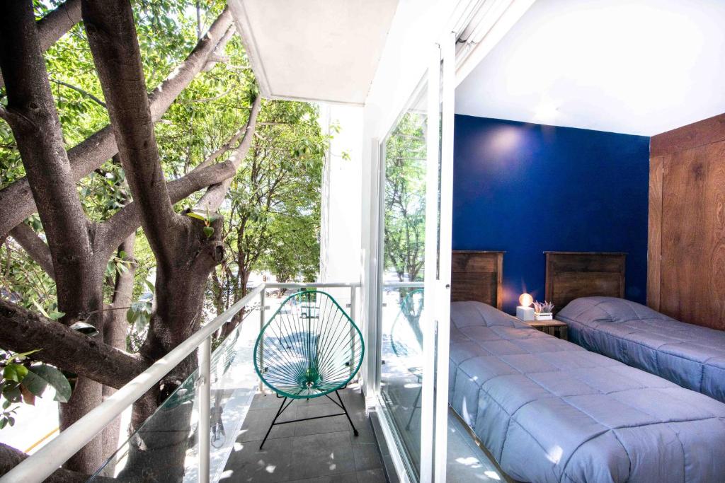 Habitación con balcón, cama y árbol. en Comfy Apartment with Private Balcony & Natural Light - Xola, en Ciudad de México