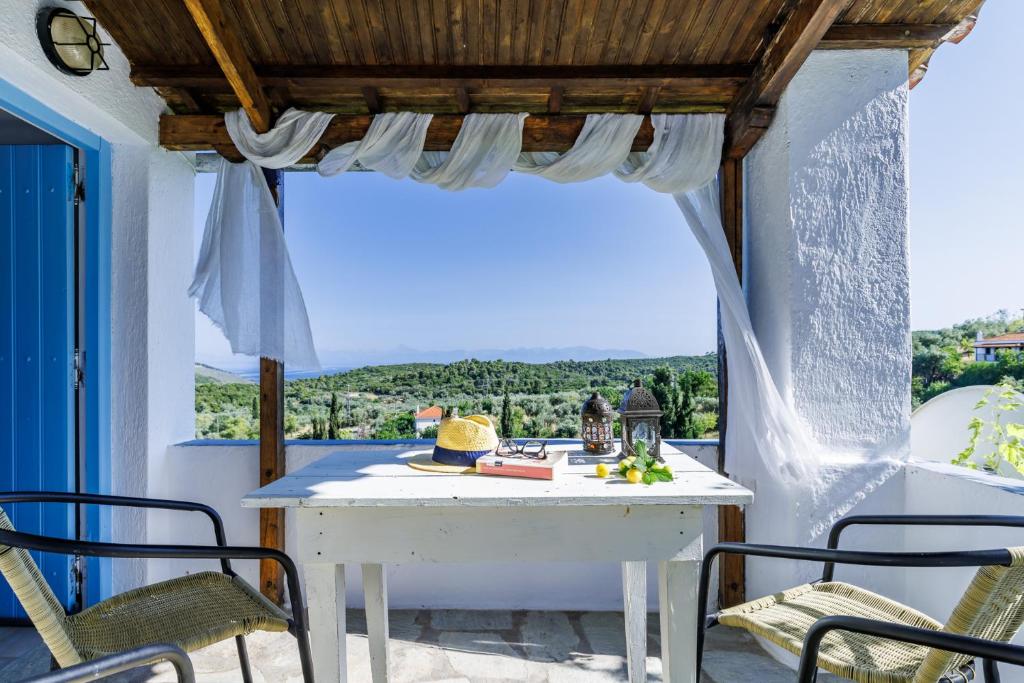 ein weißer Tisch und Stühle auf einer Veranda mit Aussicht in der Unterkunft Christina's Cottage in Skopelos