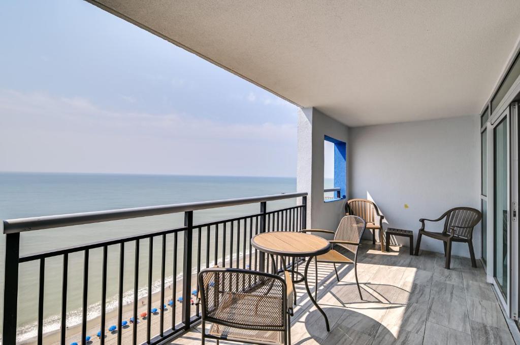 a balcony with chairs and tables and a view of the ocean at Myrtle Beach Condo with Community Pool and Ocean Views in Myrtle Beach