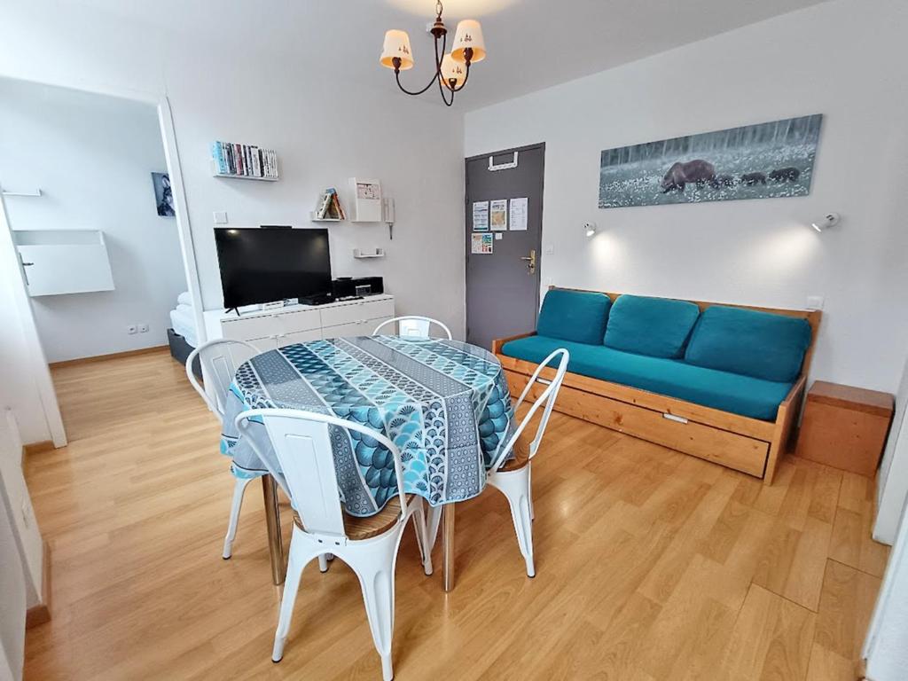 ein Wohnzimmer mit einem Tisch und einem blauen Sofa in der Unterkunft L'Isard, T2, centre Luchon, wifi, ascenseur, casier à ski, 4 personnes in Luchon