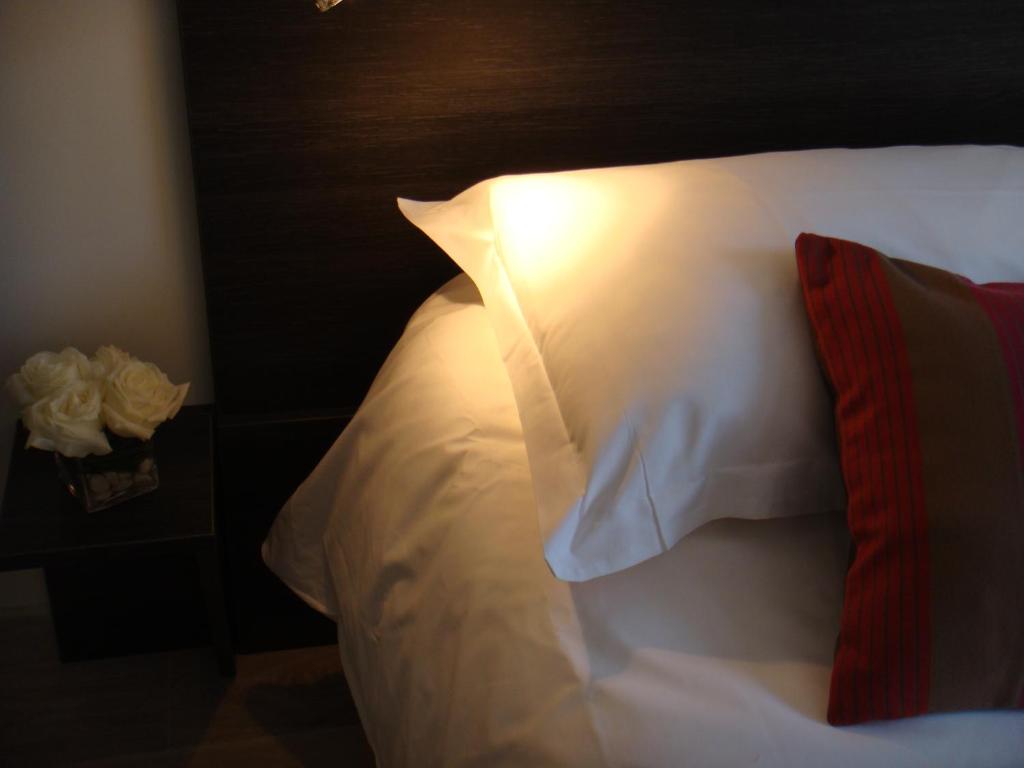 un primer plano de una cama con una almohada blanca en Côté Hôtel, en Légny