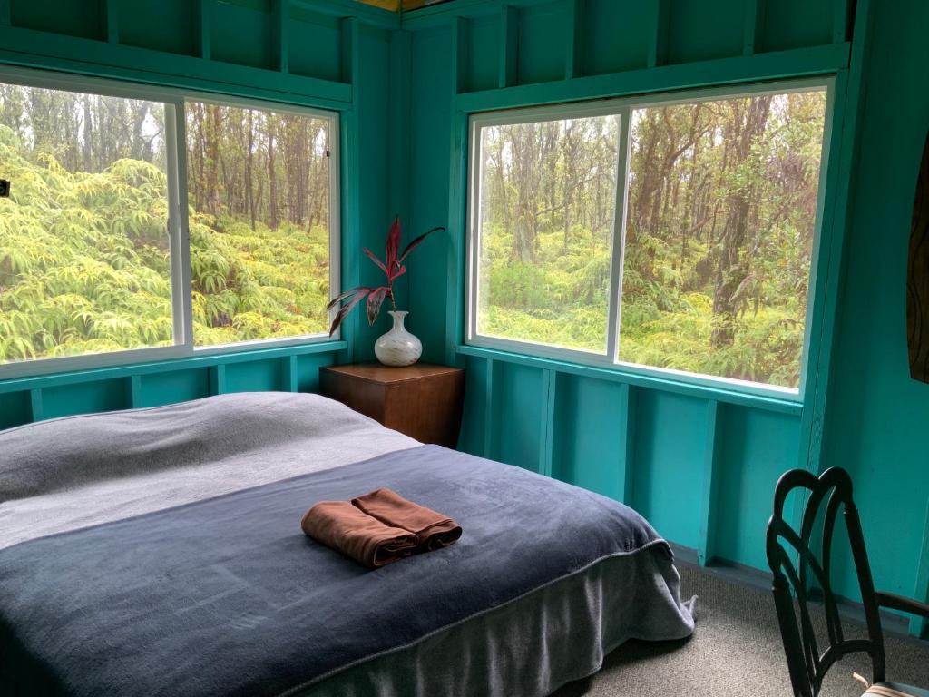 1 dormitorio con paredes azules y 1 cama con 2 ventanas en Simple Rustic studio deluxe bed in tropical fruits garden en Mountain View