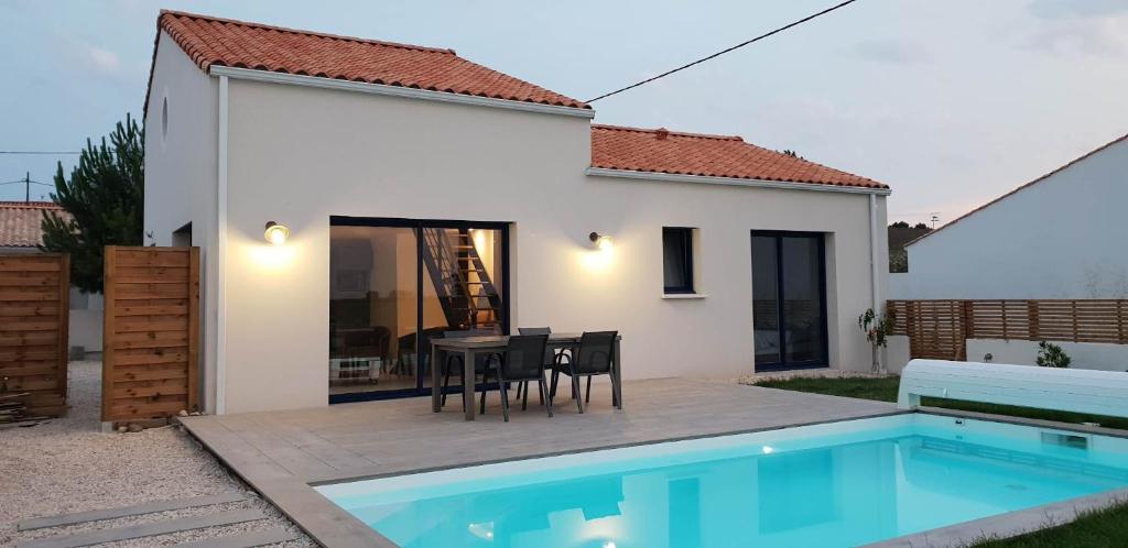 une villa avec une table, des chaises et une piscine dans l'établissement La maison du Petit Pin, à La Tranche-sur-Mer