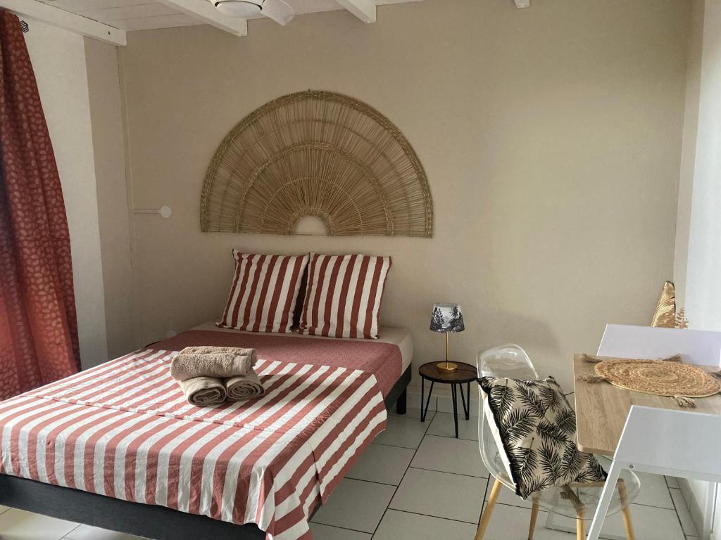 1 dormitorio con 1 cama con manta a rayas y mesa en Maison avec spa et jardin, en Schœlcher